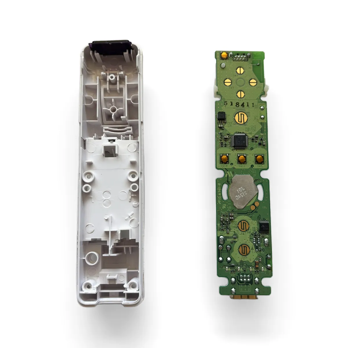 Original Wii Remote board lifted out of the bottom shell by its edges, B trigger assembly attached underneath