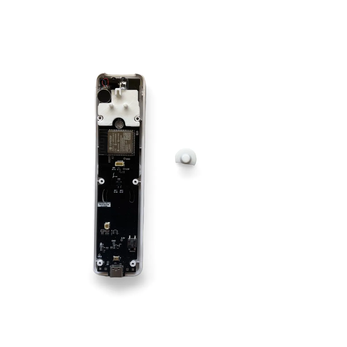 B button held with the rounded face up and the half-moon tab pointing toward the ESP32 chip