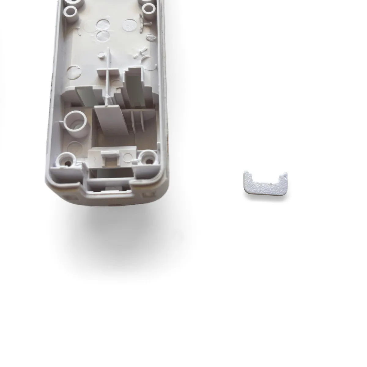 Small 3D printed port cover held next to the opening at the bottom end of the bottom shell