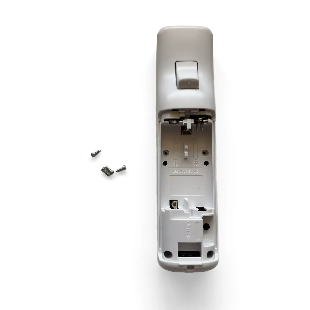 Reassembled remote face down with the four screw holes circled in red and the screws beside it