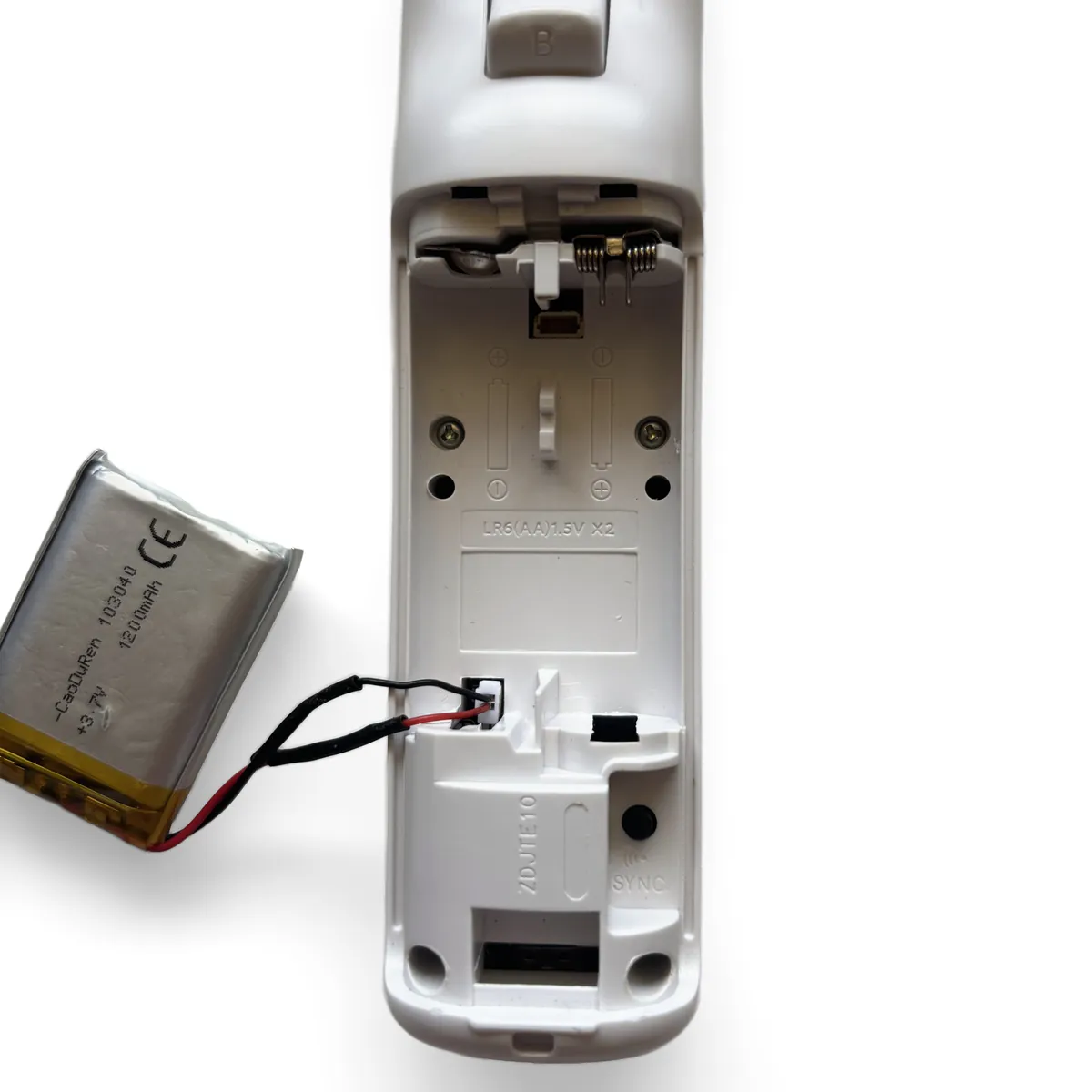 Battery connector being plugged into the socket at the bottom of the battery bay, with Negative on top and Positive below marked by arrows